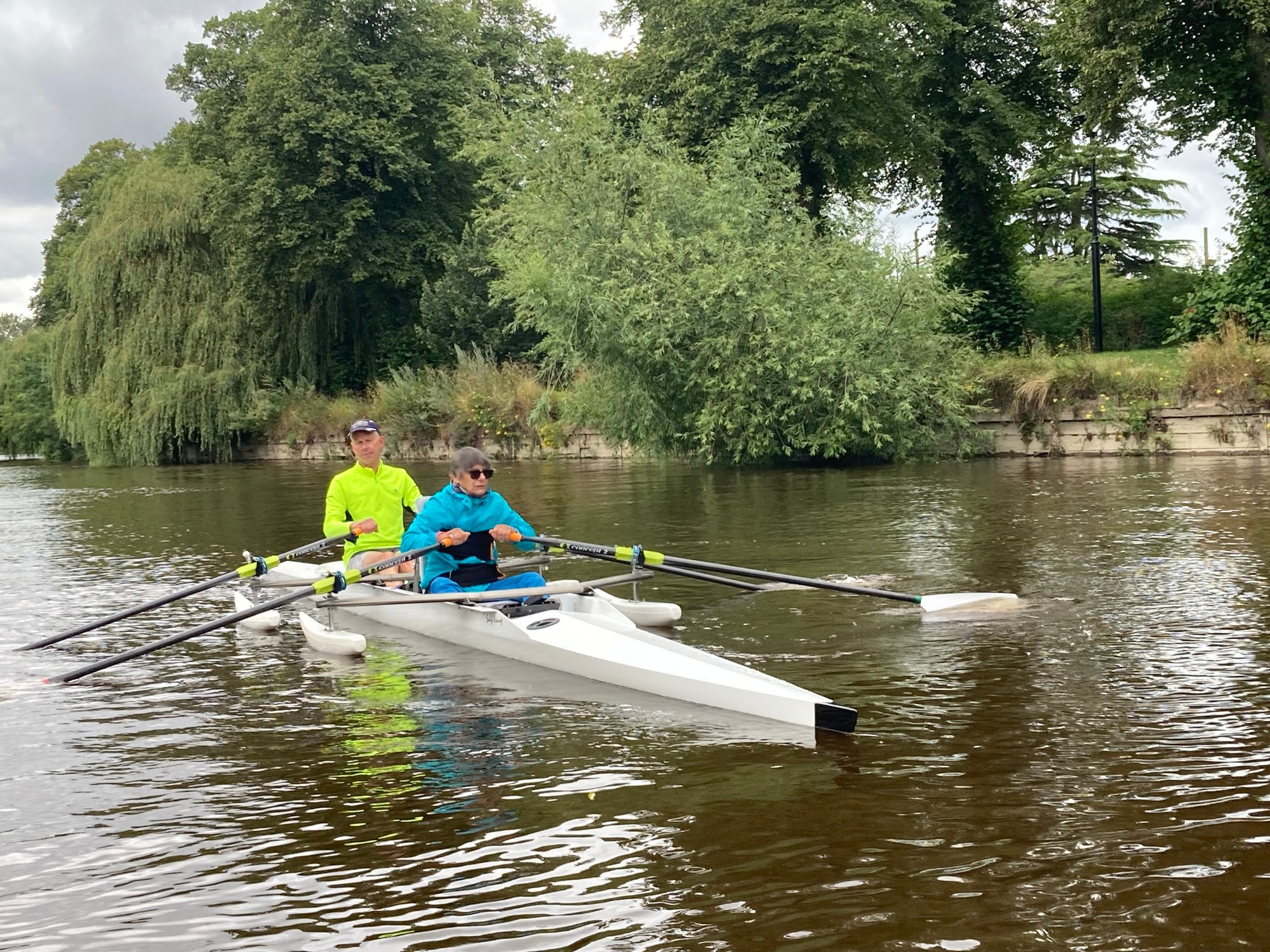 An image of a person with limited mobility using adaptive oars to row down the river easily. 