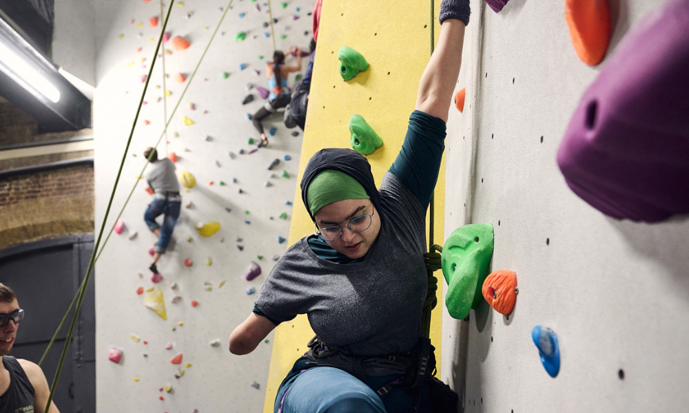 A woman with an amputated arm having a go at rock climbing. 