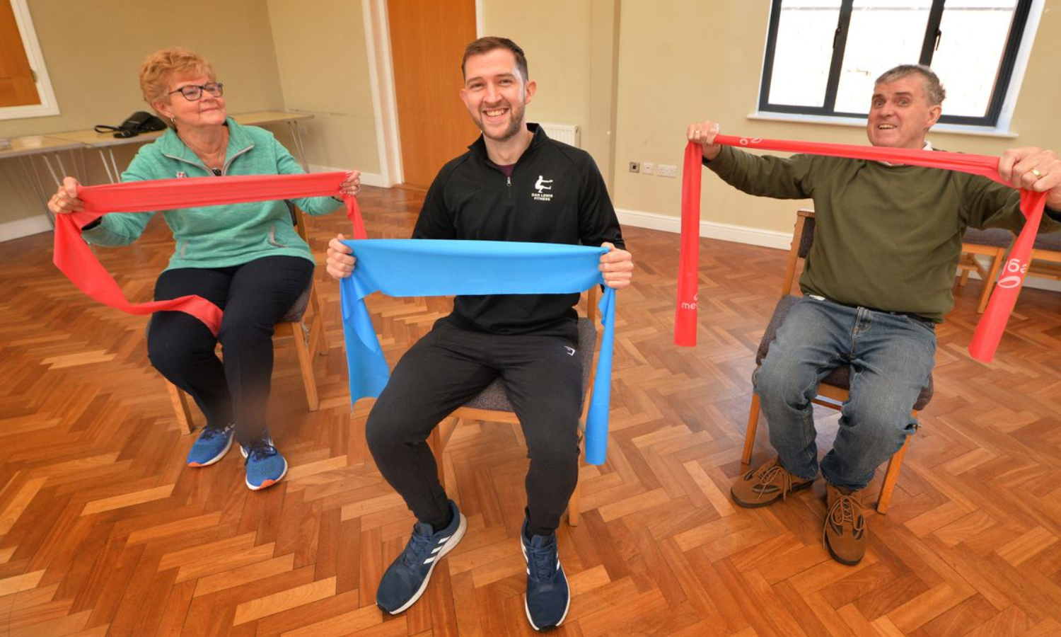 A photo of adults taking part in a strength and balance falls prevention class. The people are using exercise bands.