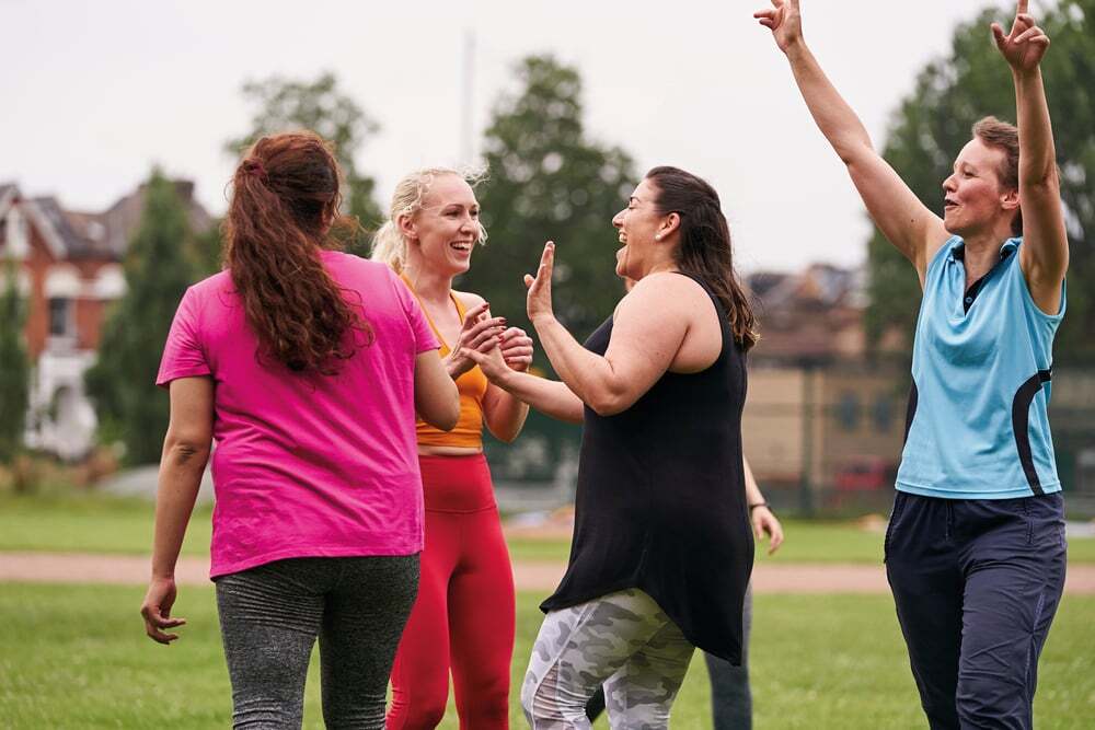A photo of females being physically outside in a green space and celebrating